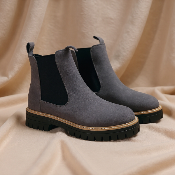 Pair of gray Chelsea boots on a beige fabric background