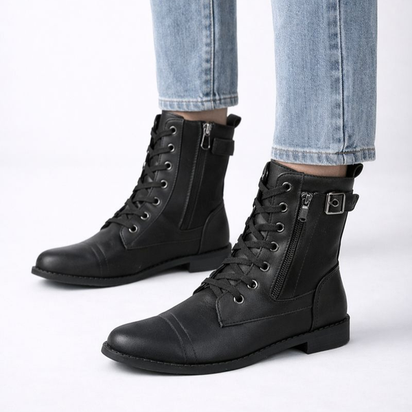 Black leather boots with zippers worn with light blue jeans on a white background