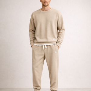 Man wearing a beige sweatshirt and pants set on a plain background