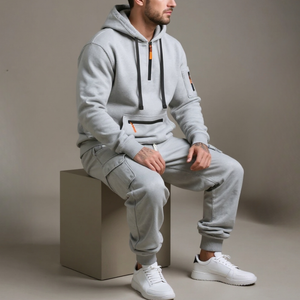 Person wearing a gray tracksuit sitting on a block with a neutral background
