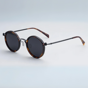 Round sunglasses with tortoiseshell frame and dark lenses on a light gray background
