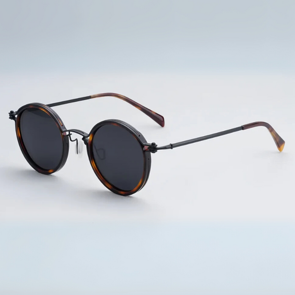 Round sunglasses with tortoiseshell frame and dark lenses on a light gray background