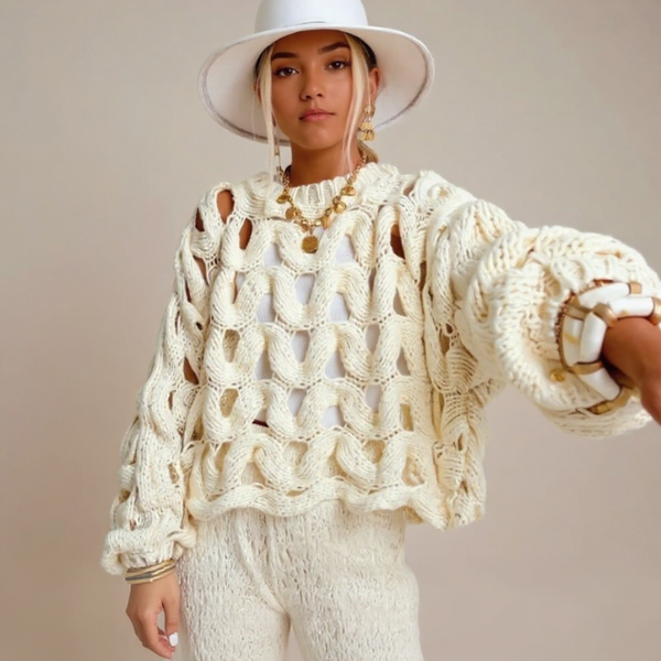 Person wearing a cream-colored knit sweater and hat against a neutral background