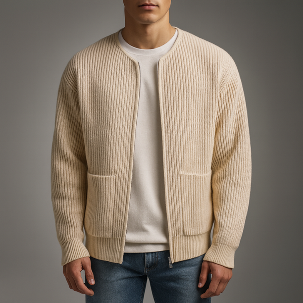 Man wearing a beige ribbed sweater over a white shirt with a gray background