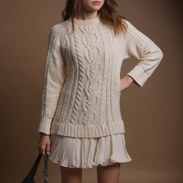 Woman wearing a cream cable knit sweater and skirt against a brown background