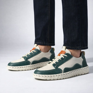Green and white sneakers worn with dark jeans on a light gray background