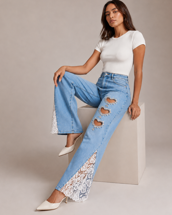 Woman wearing light blue jeans with lace details and a white top on a neutral background