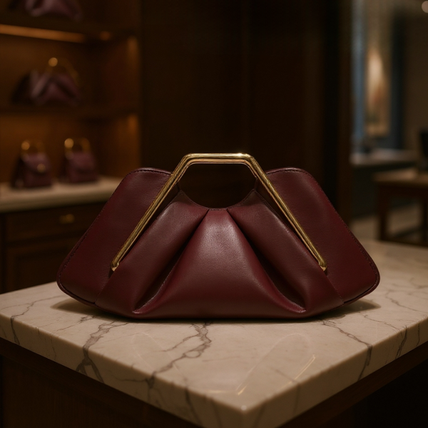 Maroon handbag with gold handle on a marble surface