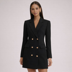 Woman wearing a black blazer dress with gold buttons on a light pink background