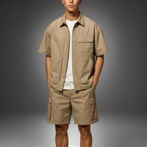 Man wearing a beige short-sleeve shirt and shorts on a gray background