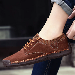 Brown suede shoe worn by a person with a blurred background
