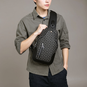 Person wearing a green shirt holding a black patterned backpack against a gray background