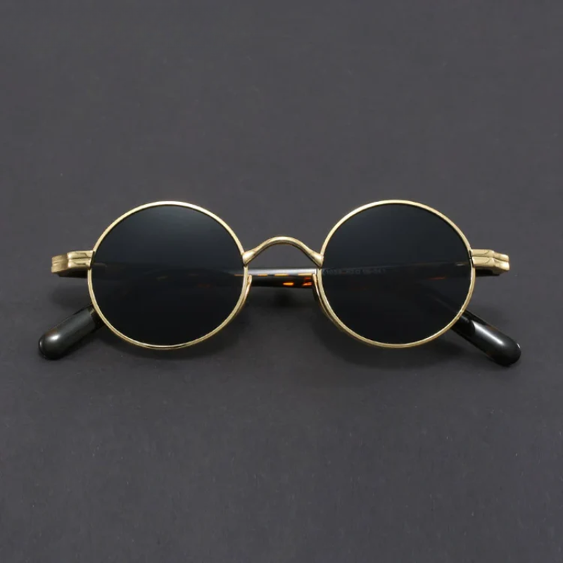 Round sunglasses with gold frame and black lenses on a dark gray background