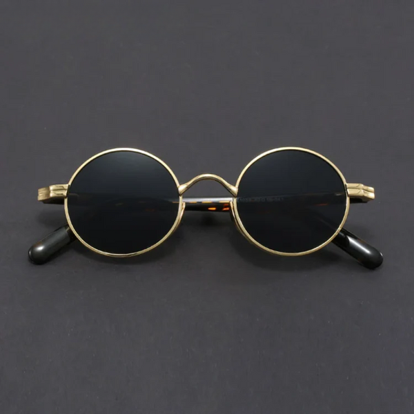 Round sunglasses with gold frame and black lenses on a dark gray background