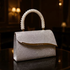 Silver glitter handbag with pearl handle on a reflective surface