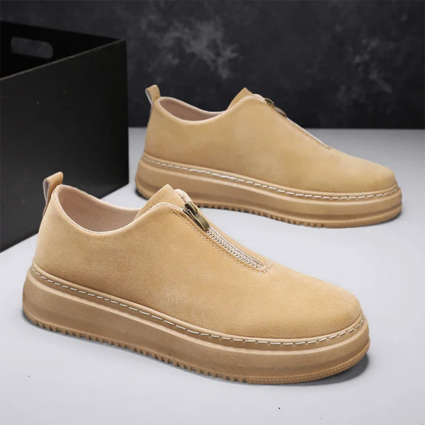 Beige slip-on shoes with a platform sole on a gray surface.