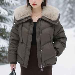 Person wearing a dark green puffer jacket with a fur-lined hood in a snowy setting