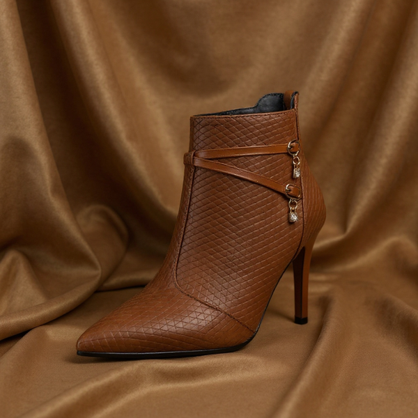 Brown leather ankle boot with a high heel on a brown fabric background