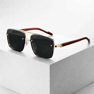 Sunglasses with gold frame and black lenses on a white surface