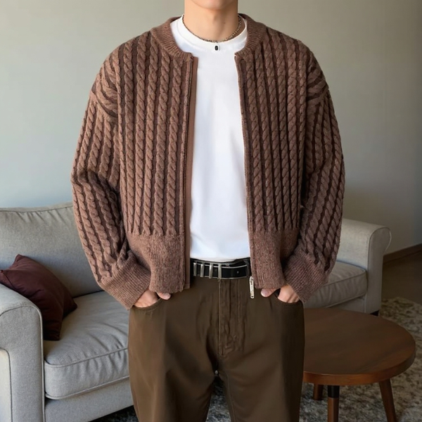 Person wearing a brown knitted cardigan over a white shirt, standing in a living room.