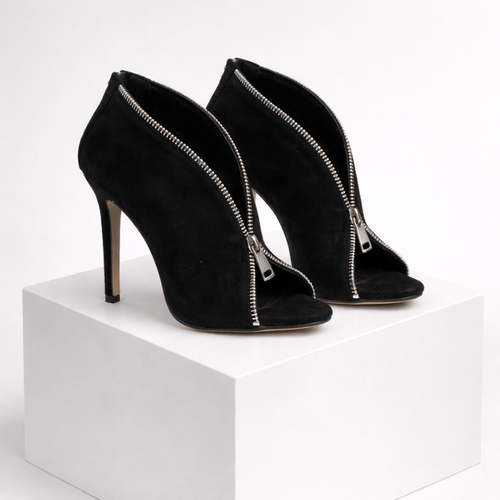 Black high-heeled shoes with zipper details on a white platform