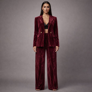 Woman wearing a burgundy velvet suit against a gray background