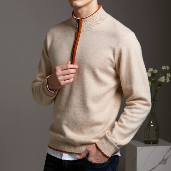 Person wearing a beige sweater with orange accents, standing against a neutral background.