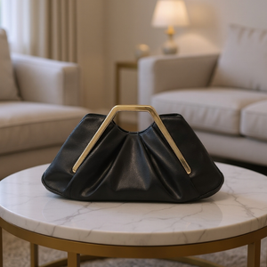 Black handbag with gold handle on a marble table in a living room setting