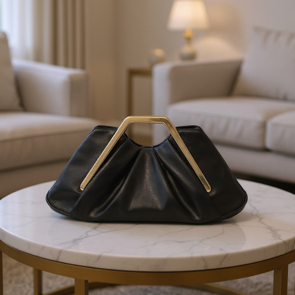 Black handbag with gold handle on a marble table in a living room setting