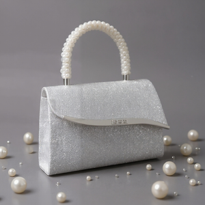 Silver glitter handbag with pearl handle and scattered pearls on a gray background