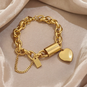 Gold chain bracelet with heart charm on a beige fabric background