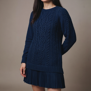 Navy blue cable knit sweater dress worn by a person on a brown background