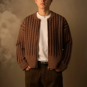 Person wearing a brown knitted cardigan over a white shirt against a neutral background