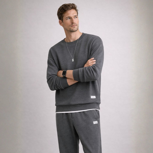 Man wearing a gray sweatshirt and pants with a plain background