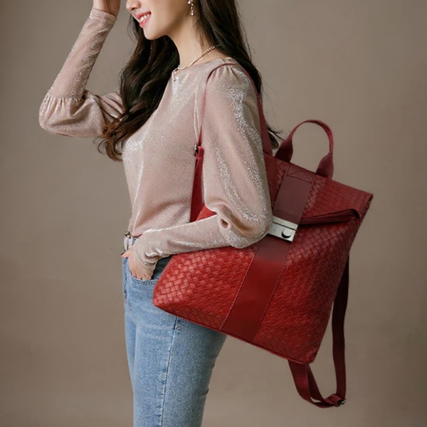 Woman holding a red textured handbag against a neutral background
