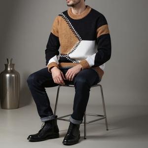 Man wearing a patterned sweater sitting on a chair with a neutral background