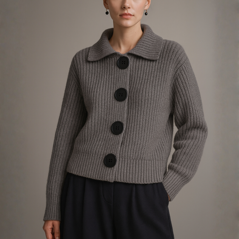 Person wearing a gray ribbed sweater with black buttons on a plain background