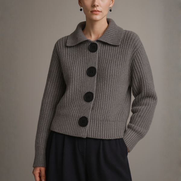 Person wearing a gray ribbed sweater with black buttons on a plain background
