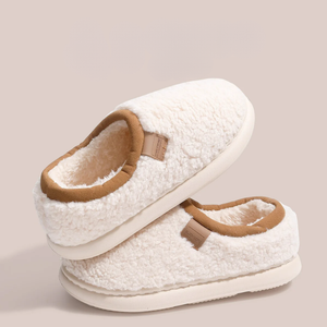 Pair of white slippers with brown accents on a beige background