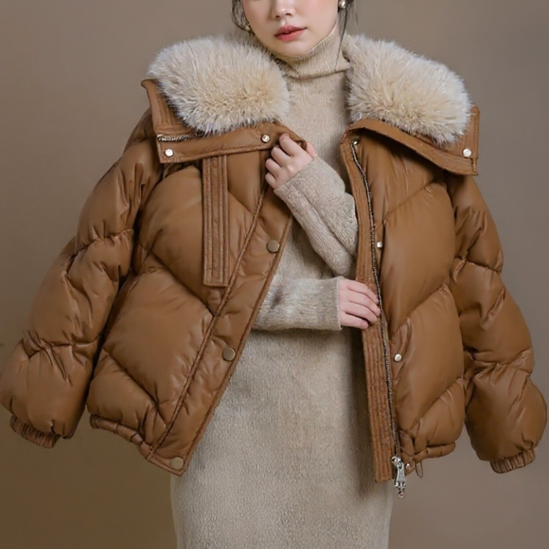 Person wearing a dark green puffer jacket with a fur-lined hood in a snowy setting