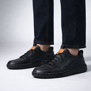 Black leather shoes worn with dark jeans on a light gray background