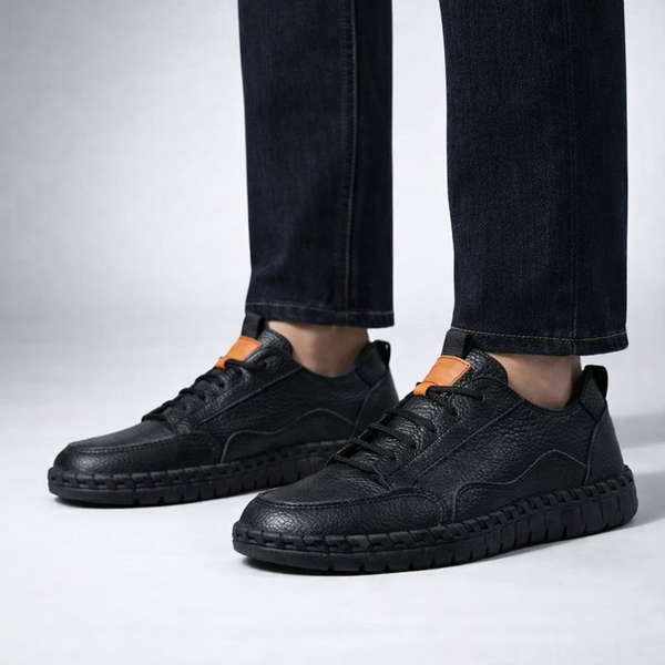 Black leather shoes worn with dark jeans on a light gray background