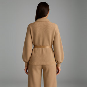 Woman wearing a beige ribbed knit outfit on a gray background