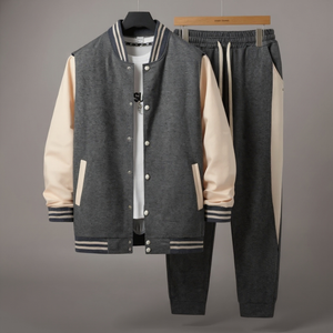 Gray varsity jacket with beige sleeves and black pants on a gray background