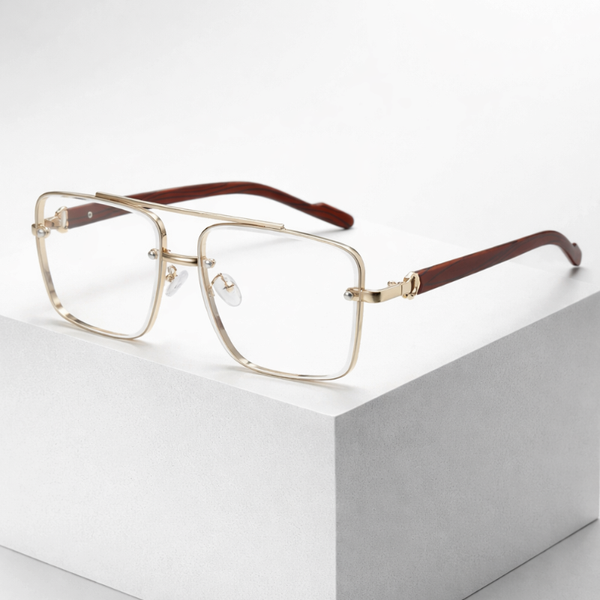 Gold-framed eyeglasses with brown temple tips on a white surface
