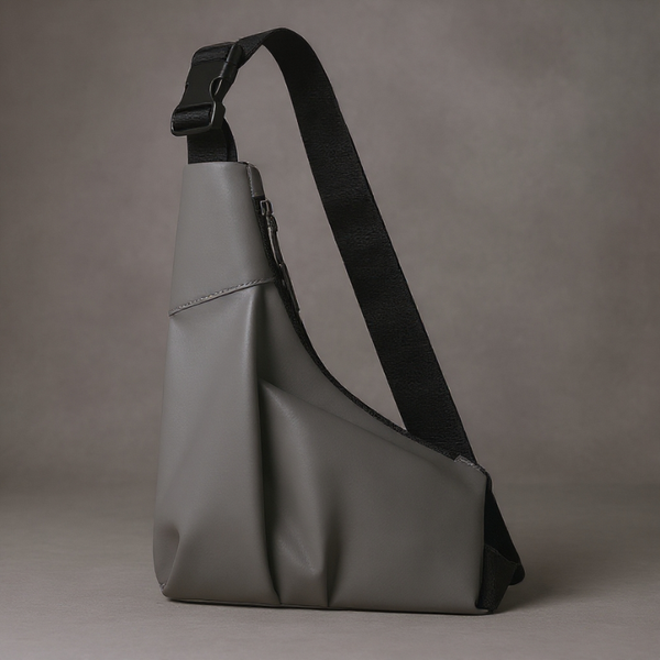 Gray sling bag with a black strap on a gray background