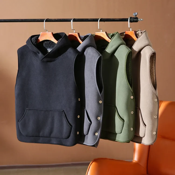 Four vests in black, gray, green, and beige hanging on a rack against a brown wall.