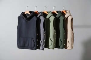 Five vests in black, gray, green, and beige on hangers against a gray background