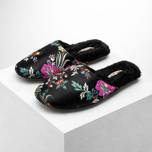 Black slippers with colorful floral embroidery on a light gray background