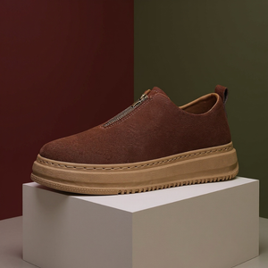Brown slip-on shoe with a thick sole on a white block against a gradient background